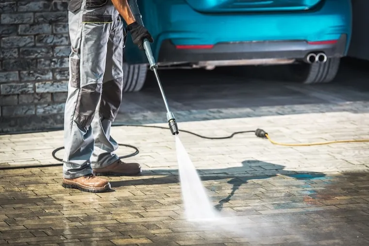 A pressure washing business owner reviewing job footage on a computer with a camera and tripod on the desk, in a natural documentary style.