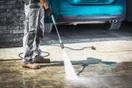 A pressure washing business owner reviewing job footage on a computer with a camera and tripod on the desk, in a natural documentary style.