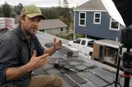 A roofing contractor explaining a technique to an off-frame camera in the workshop, in a natural documentary style.