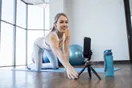 An instructor recording a short vertical yoga clip on a phone in a home studio with a ring light, in a natural documentary style.