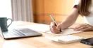 An accountant filling out IRS registration forms beside a laptop showing an e-file application, in a natural documentary style.