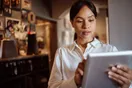 A caterer reviewing a health department permit application and a commissary kitchen agreement at a desk with a laptop, in a natural documentary style.