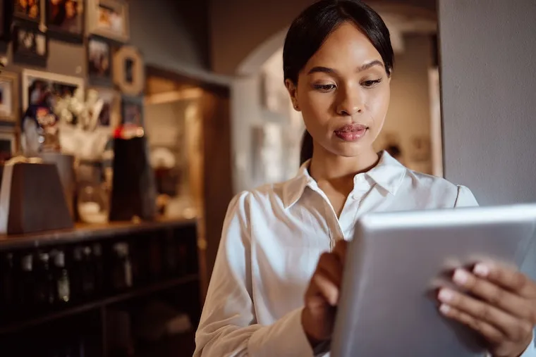 A caterer reviewing a health department permit application and a commissary kitchen agreement at a desk with a laptop, in a natural documentary style.