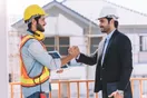 A construction company owner reviewing a project schedule on a laptop in a job-site trailer, in a natural documentary style.