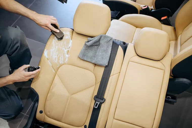 A hand holding a phone showing a car wash Facebook page with customer reviews, parked next to a freshly washed car, in a natural documentary style.
