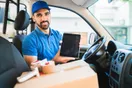 A courier checking a phone with a Facebook messaging thread open while standing beside a delivery van, in a natural documentary style.