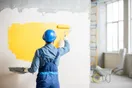 A painter photographing a freshly finished interior wall with a phone for social media, in a natural documentary style.