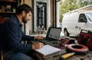 An electrician reviewing an ad dashboard on a laptop at a workbench, in a natural documentary style.