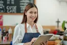 A caterer reviewing a Google Ads campaign dashboard on a laptop at a kitchen prep table, in a natural documentary style.