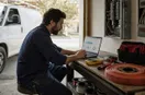 An electrician studying an ads dashboard with charts on a laptop, in a natural documentary style.