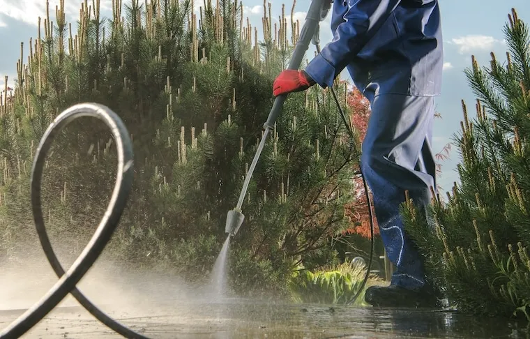 A laptop showing a Google Ads campaign dashboard next to a pressure washing work order and phone, documentary style on a desk.