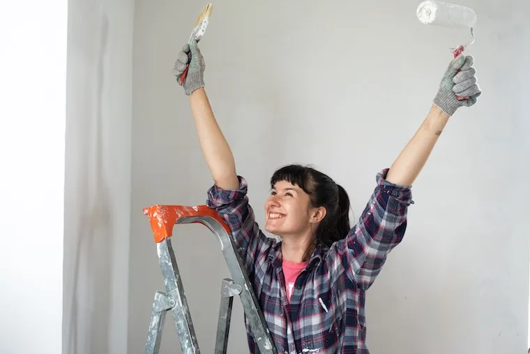 A painting crew loading up at the end of a workday beside a finished repainted house, in a natural documentary style.