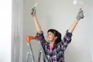 A painting crew loading up at the end of a workday beside a finished repainted house, in a natural documentary style.