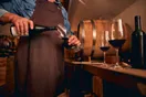 Rows of oak barrels in a dim winery cellar with a tasting glass on a barrel head, in a documentary style.