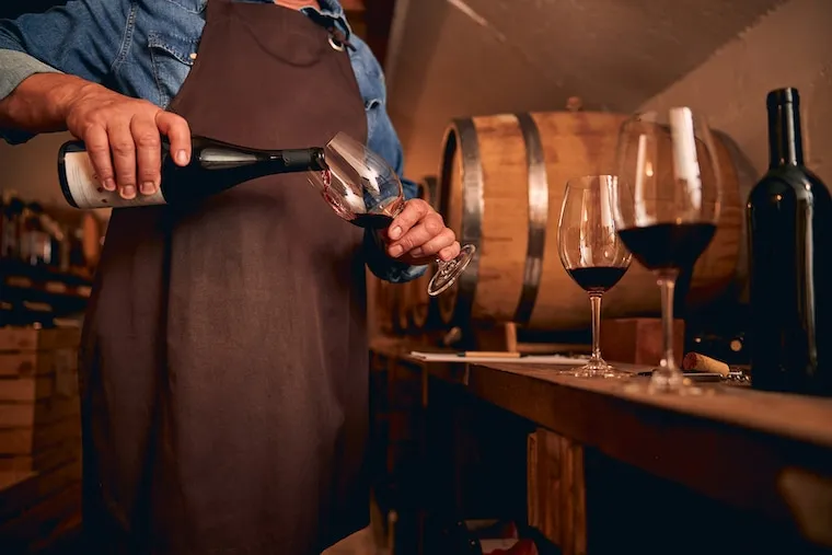 Rows of oak barrels in a dim winery cellar with a tasting glass on a barrel head, in a documentary style.