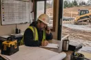 A site contractor coordinating the day's schedule at a small dispatch desk, in a natural documentary style.