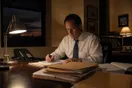 A solo attorney sits at a small office desk late in the evening beside a phone that has stopped ringing, in a natural documentary style.