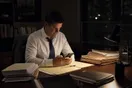 A solo attorney sits in his office late in the evening checking his phone, case files stacked on the desk under a single lamp.