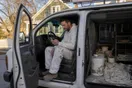 A painter sits in his van at the end of the day looking at a phone with no new voicemails, in a natural documentary style.