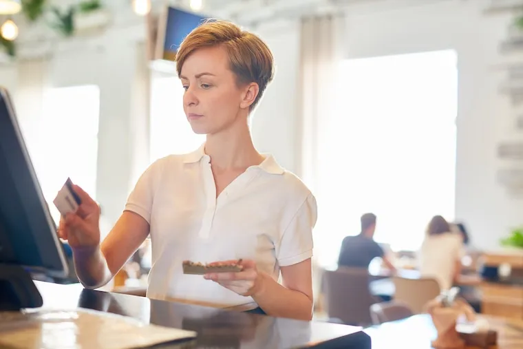 A caterer reviewing a printed event proposal and calculator beside plated sample dishes, in a natural documentary style.