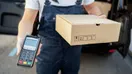 A courier reviewing an invoice on a tablet beside a parked delivery van, in a natural documentary style.
