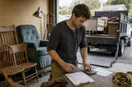 A junk removal operator working out a rate card and a customer invoice at a workbench, in a natural documentary style.