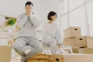 Two movers loading a rented box truck with a hand dolly on a driveway, in a natural documentary style.