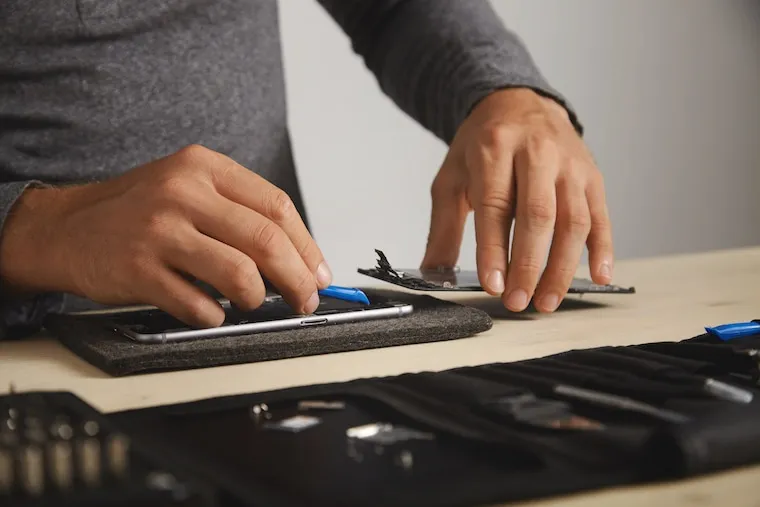 A technician following a step-by-step teardown on a benchtop with tools laid out in order, in a natural documentary style.