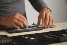 A technician following a step-by-step teardown on a benchtop with tools laid out in order, in a natural documentary style.