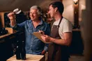 A winemaker checking a fermentation tank with a clipboard during harvest crush, in a natural documentary style.
