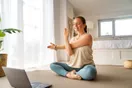 A new yoga studio owner laying out mats and checking a tablet in an empty studio before opening, documentary style.