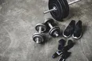 Rows of power racks, barbells, and loaded weight plates on a rubber gym floor, in a natural documentary style.