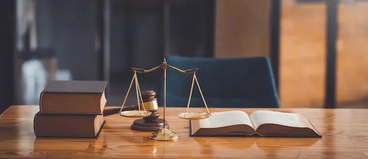 A tidy law office desk with a laptop, dual monitor, scanner, and stacked case files, in a natural documentary style.