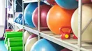 Neatly organized yoga blocks, straps, and bolsters stacked on wooden shelves along a studio wall, in a natural documentary style.