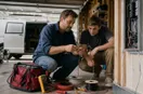 An electrician showing a new hire a tool technique up close, in a natural documentary style.
